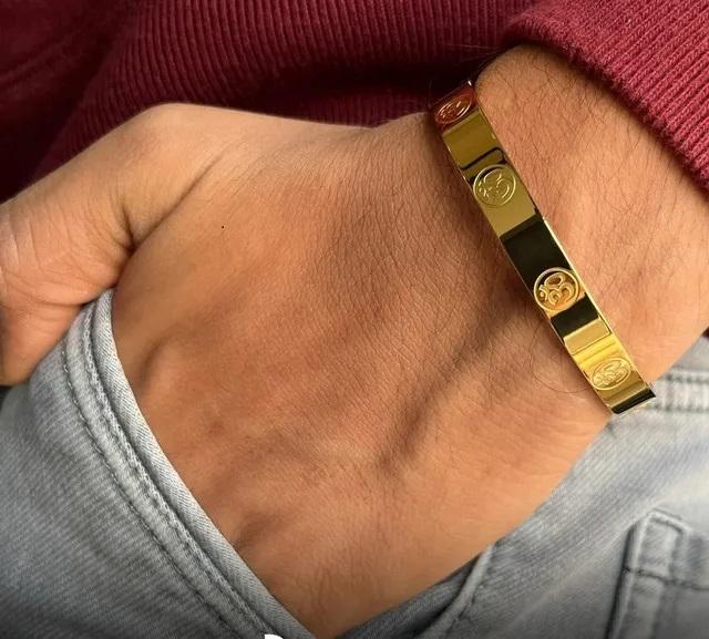 Carved Om Gold Plated Bracelet displayed on a hand with a stylish outfit for a trendy look