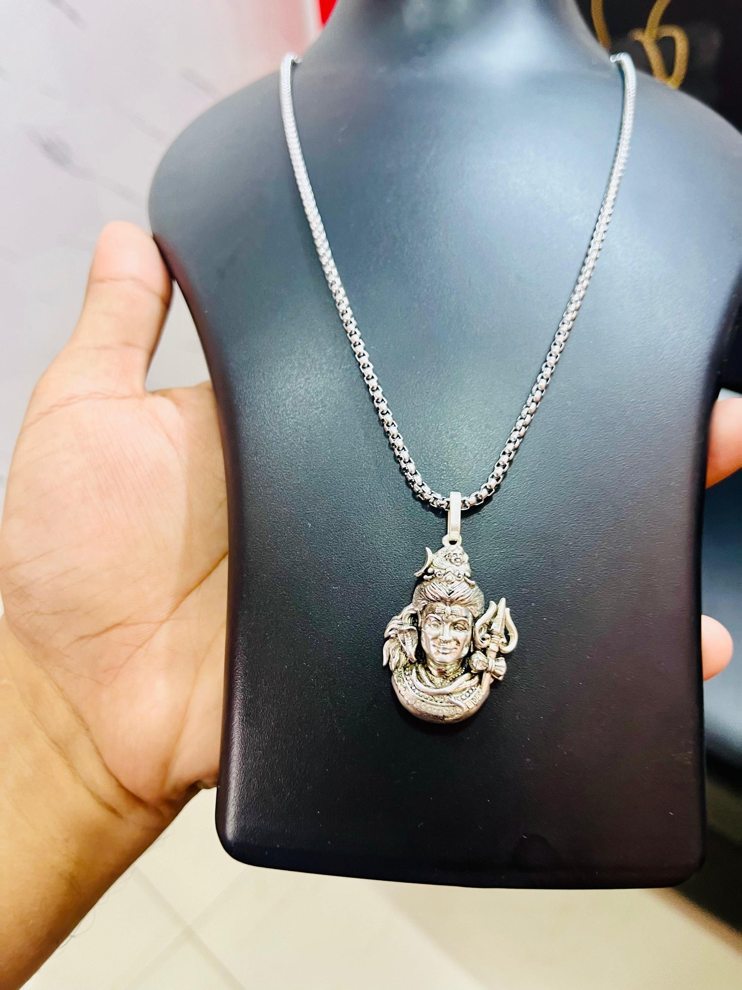 Silver Mahadev pendant necklace showcasing intricate design on a classic chain display