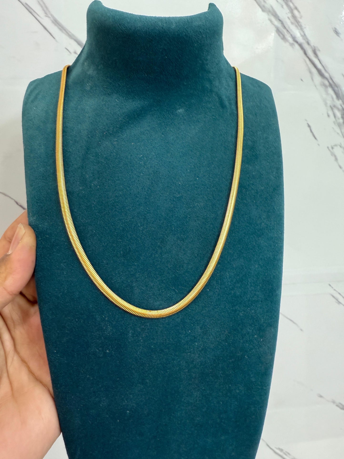 Sleek gold-tone men's fashion jewelry chain displayed on a velvet neck stand