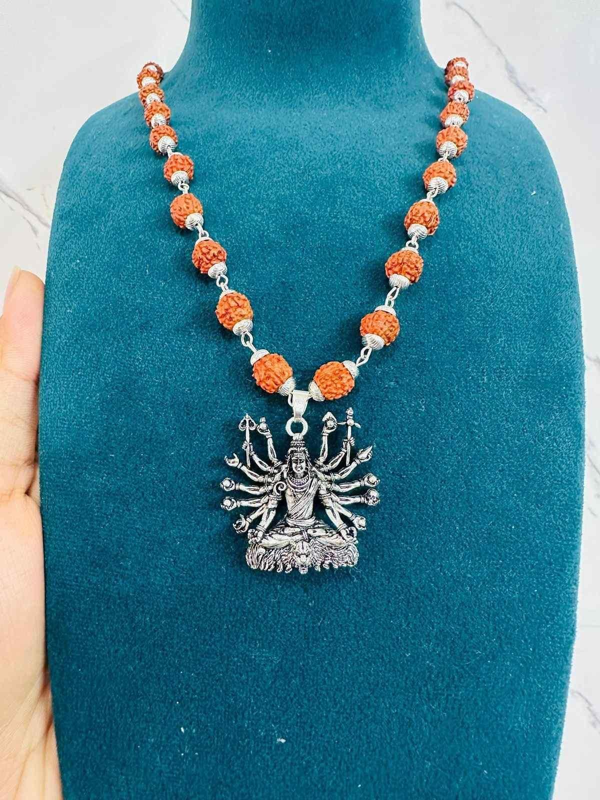 Sitted Shiva silver pendant on a beaded necklace featuring orange and silver elements