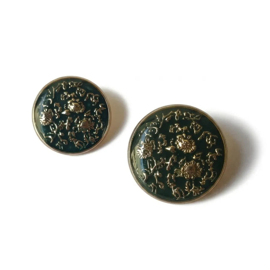 A professional studio shot of Gleemify luxury emerald green and gold buttons for blazers and coats, displayed with natural soft shadows.
