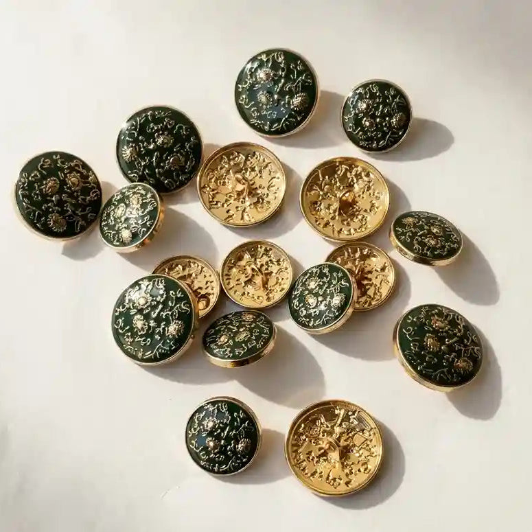 Extreme close-up of Gleemify dark green enamel buttons highlighting the intricate embossed gold floral arabesque pattern and professional finish.