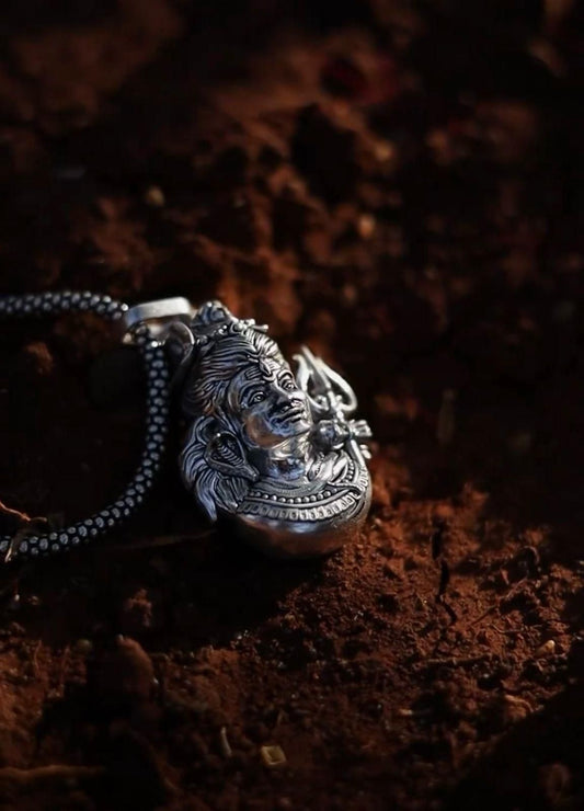Silver Mahadev pendant necklace featuring intricate design and craftsmanship on a textured background