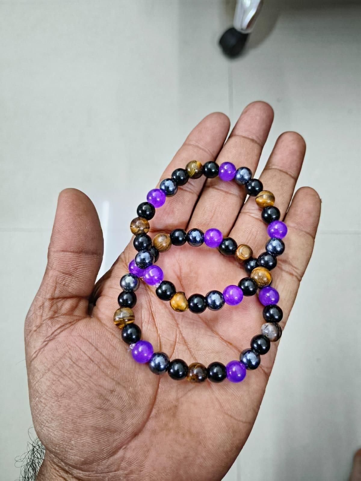 Natural stone bracelet set featuring purple, black, and golden beads on a hand.