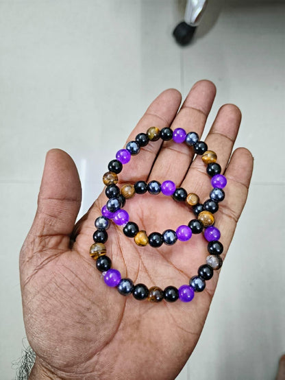 Natural stone bracelet set featuring purple, black, and golden beads on a hand.