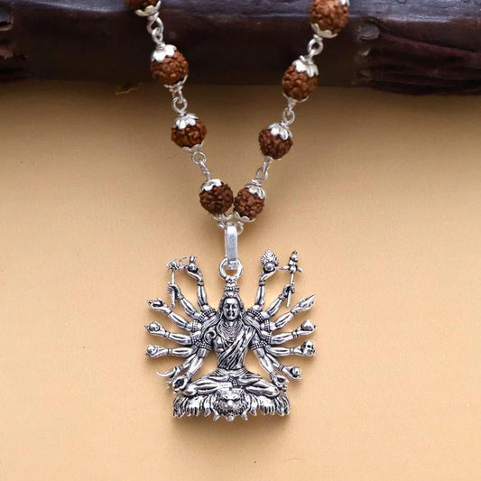 Sitted Shiva silver pendant with intricate detailing and eight arms, hanging on a beaded necklace
